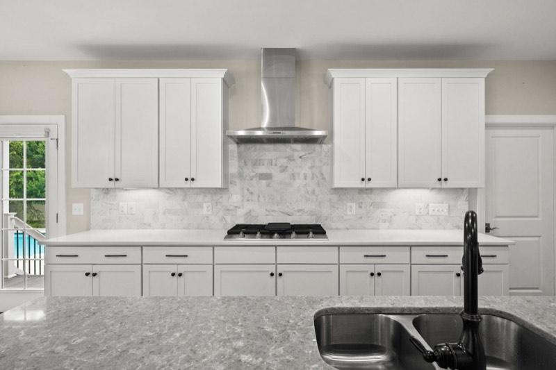 Gas range, hood and tiled backsplash